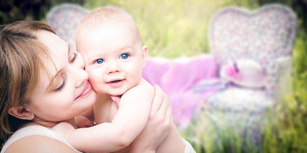 Mutter hält ihr Baby auf einer Wiese im Arm