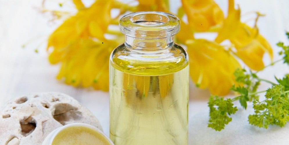 Fläschchen mit ätherischem Öl vor gelben Blüten