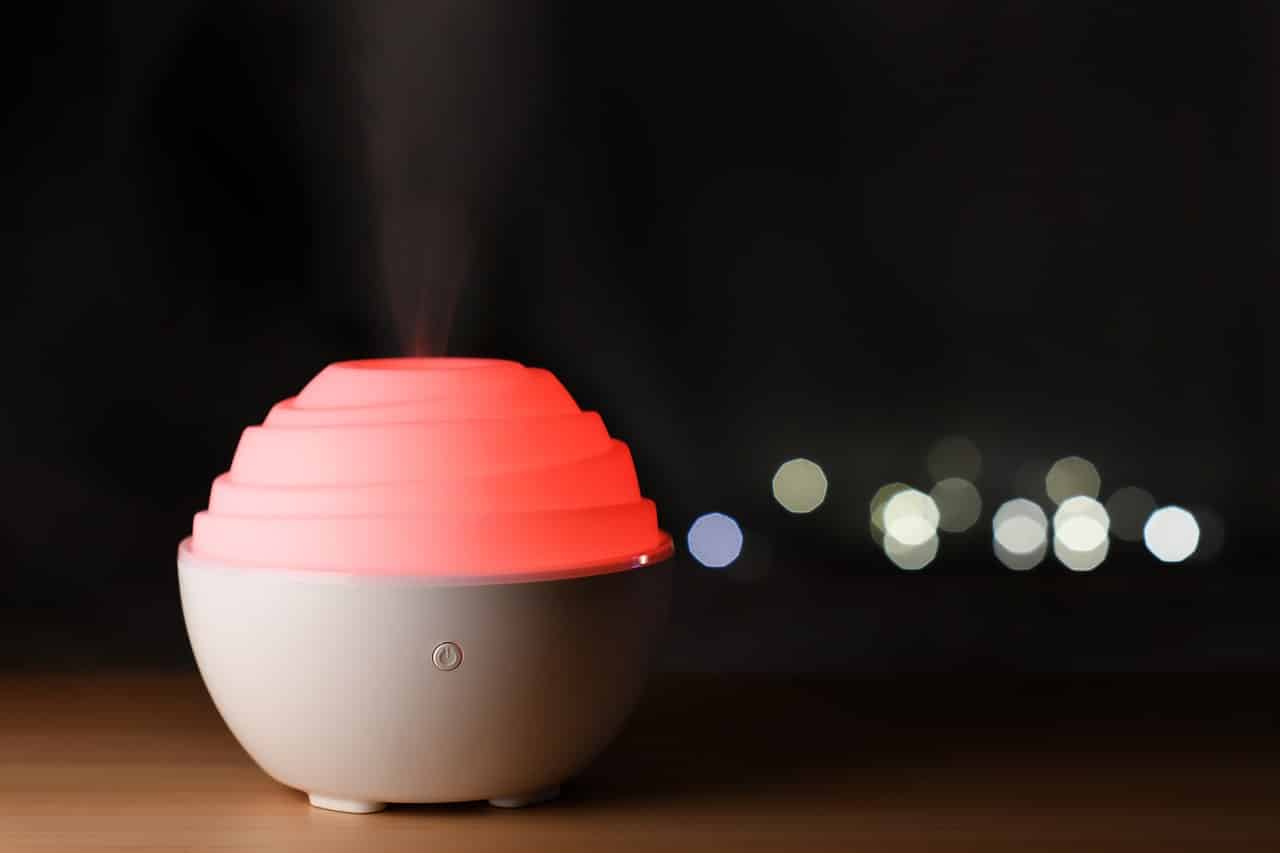 Diffuser für ätherische Öle der auf einem Tisch steht vor dunklem Hintergrund.