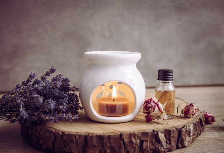 Duftlampe auf einem Stück Holz mit Lavendel und einer Flasche ätherischem Öl