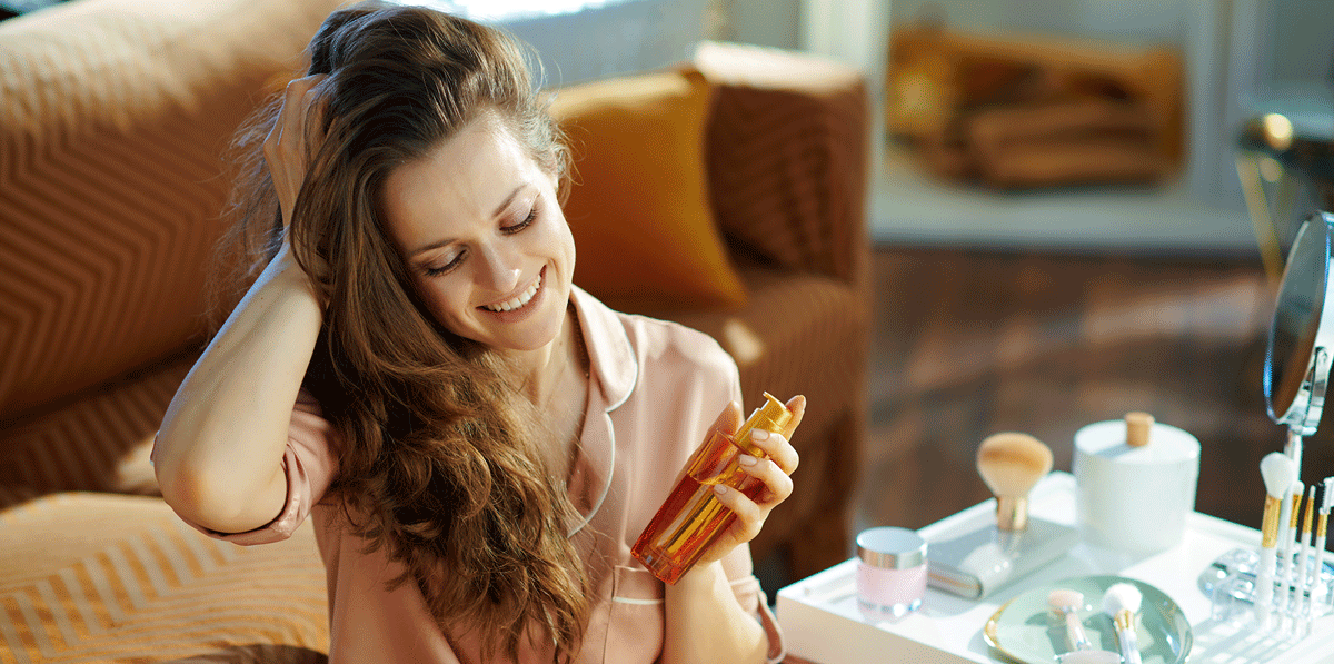 Junge Frau mit einer Flasche Öl in der Hand bei der Haarpflege