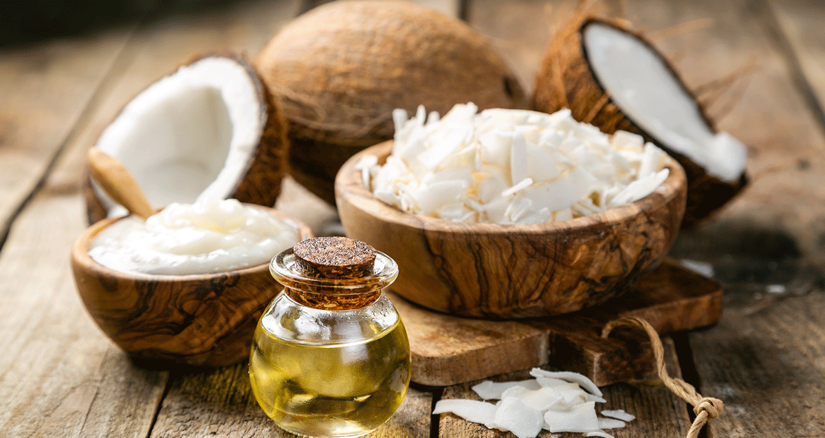 Kokosöl vor einer Schale mit Kokosraspeln und einer Kokosnuss