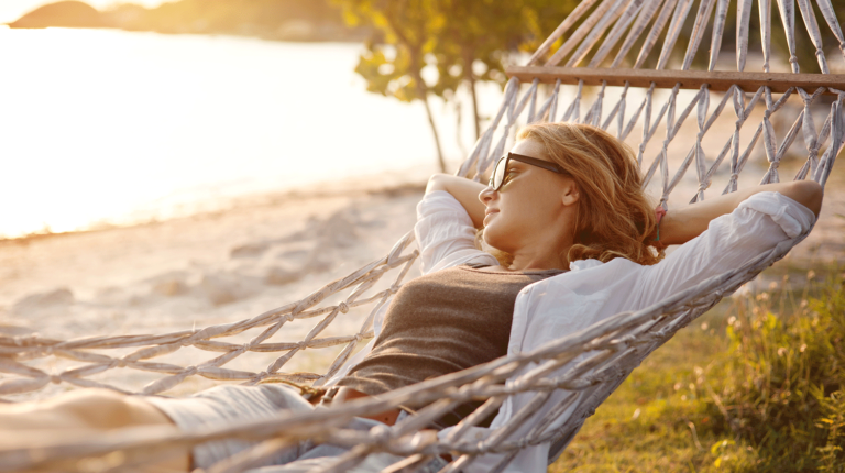 Junge Frau sonnt sich am Strand in einer Hängematte