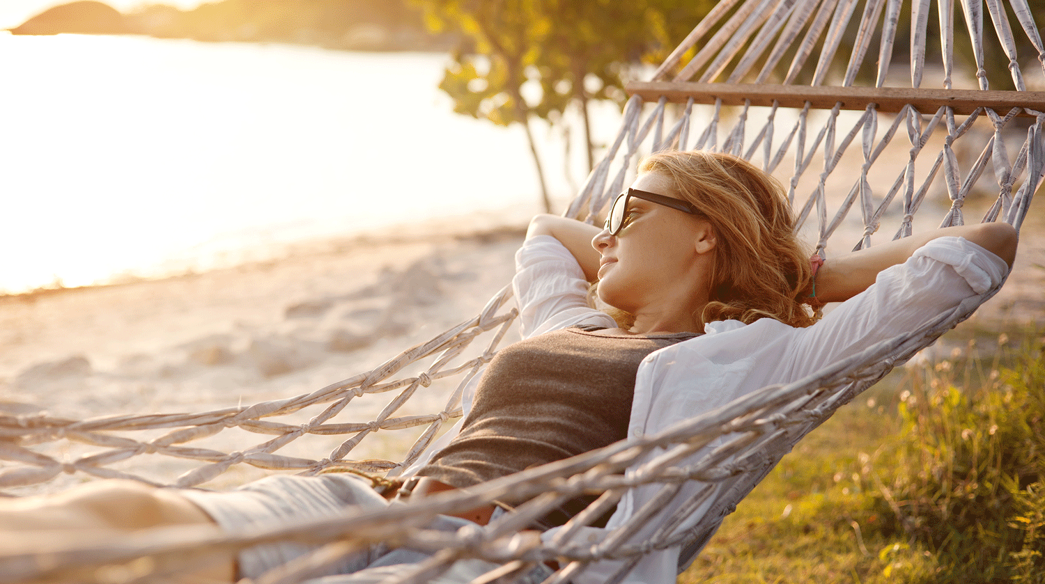 Junge Frau sonnt sich am Strand in einer Hängematte