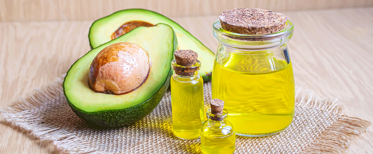 Eine aufgeschnittene Avocado und Fläschchen mit Öl auf einem Tisch