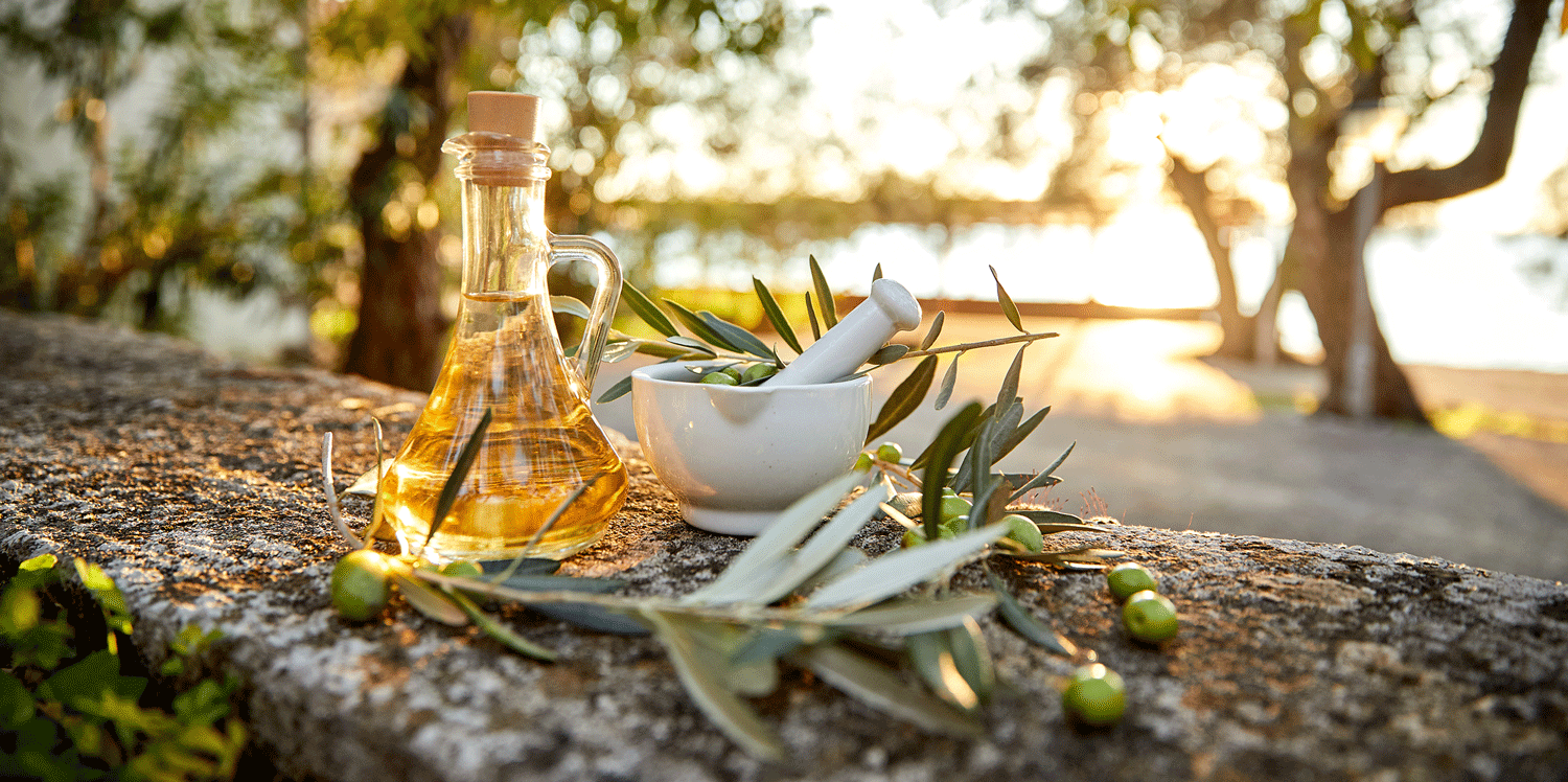 Olivenöl mit Oliven und Blättern auf einem Holzuntergrund
