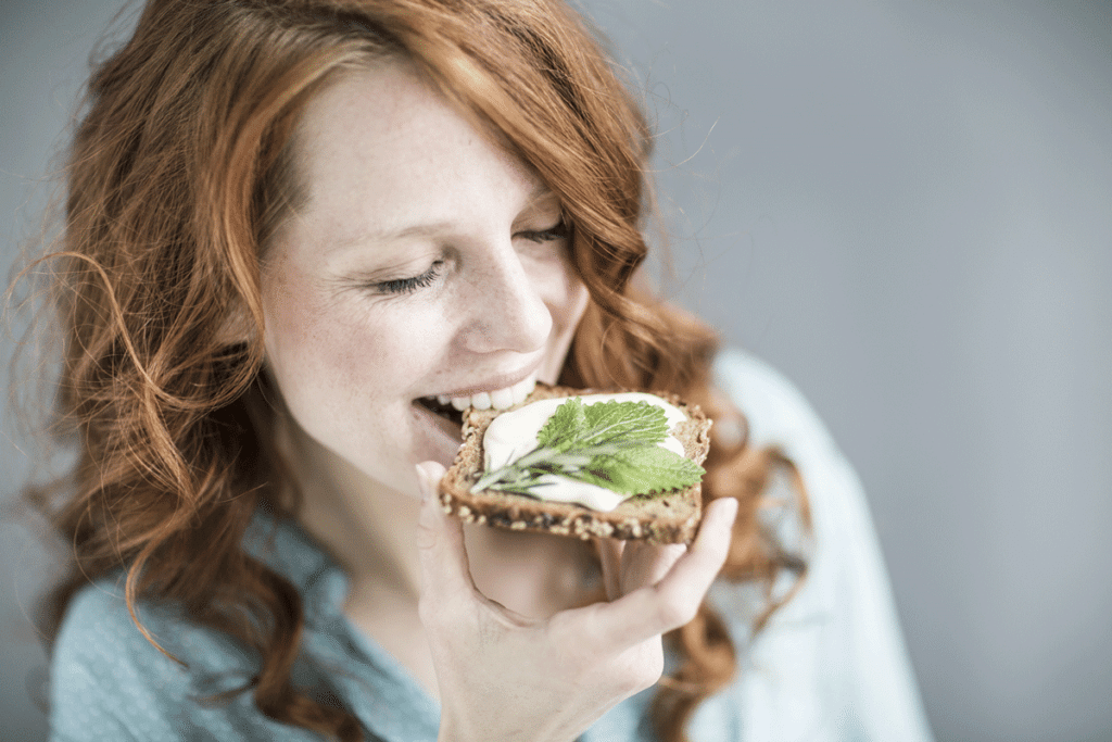 Junge Frau beißt in ein Vollkornbrot mit Frischkäse