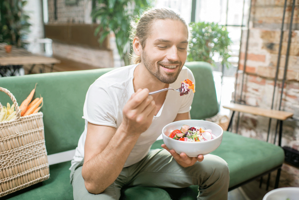 Junger Mann ist einen Salat