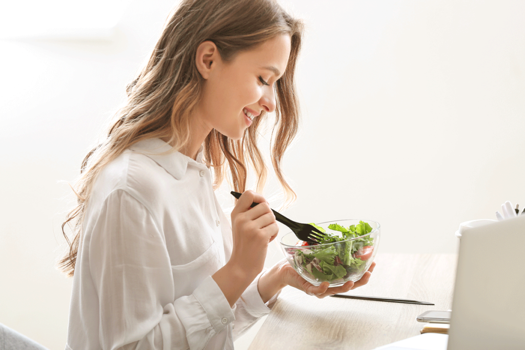 Junge Frau isst grünen Salat mit vielen Vitaminen