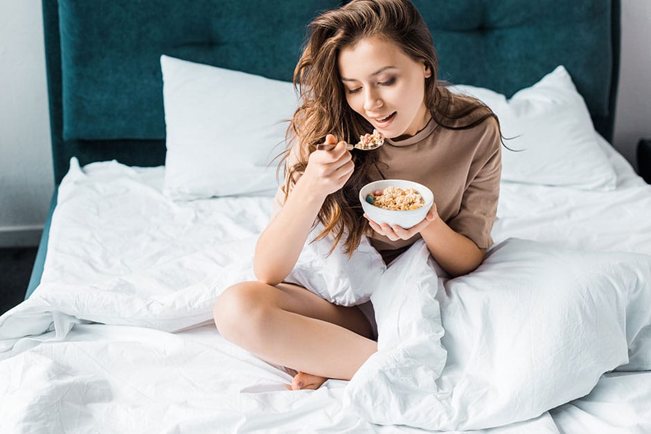 Eine Frau ist im Bett Haferflocken, um Vitamin B1 aufzunehmen