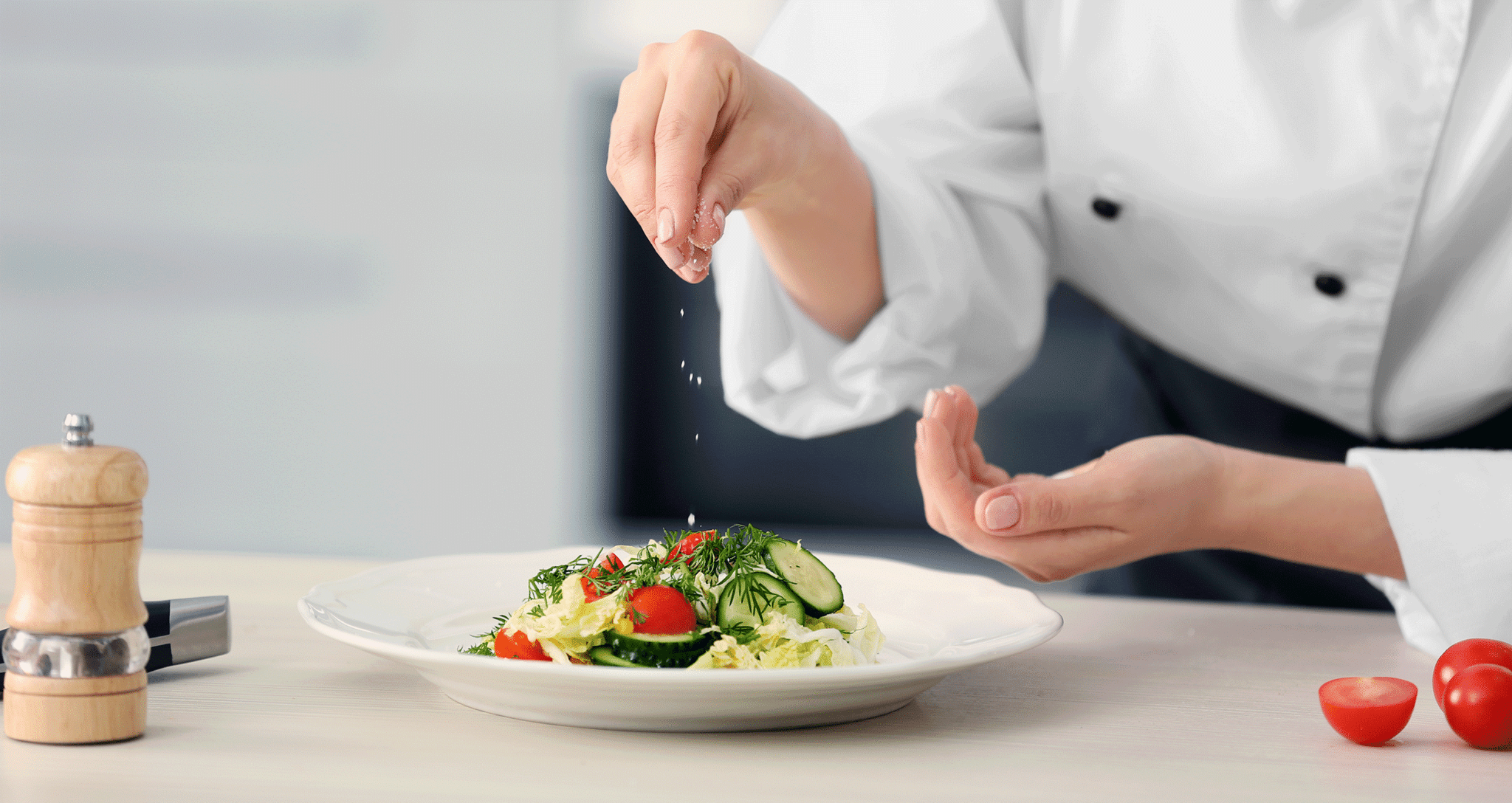 Köchin streut Salz über ein Teller mit Gemüse
