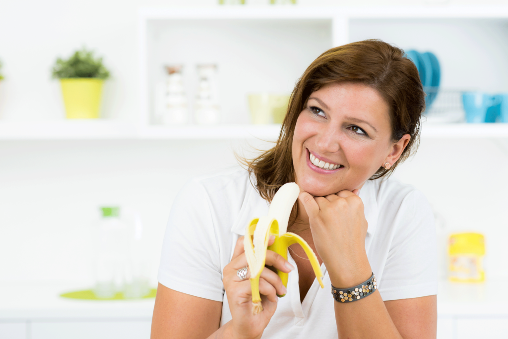 Lächelnde Frau isst eine Banane