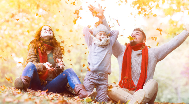 Junge Familie spielt im Herbst mit Blättern