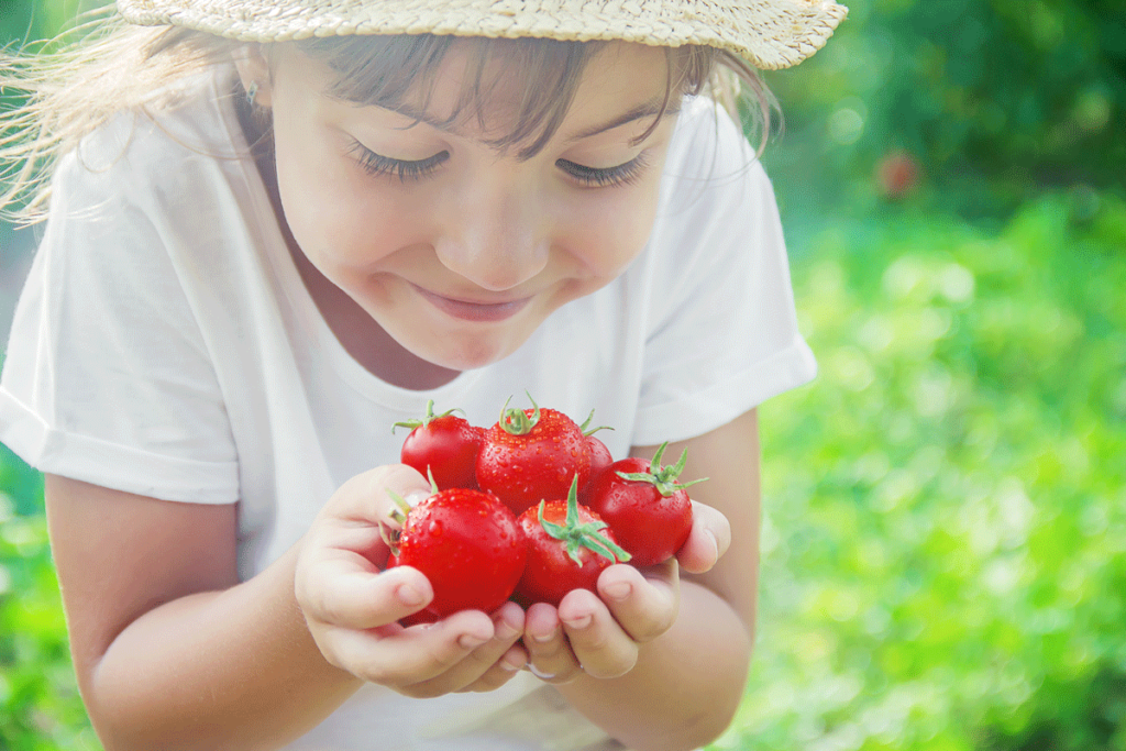 Junges Mädchen auf einer Wiese hält Erdbeeren in der Hand